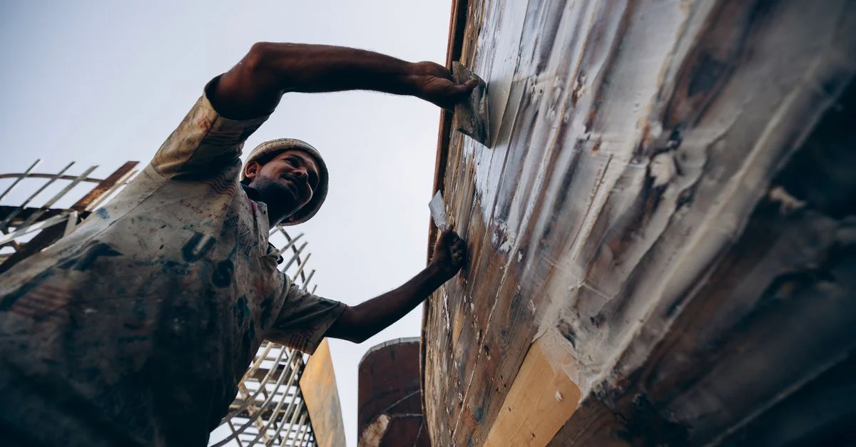 Un artisan restaure habilement un bateau en bois à Damiette, en Égypte, mettant en valeur le savoir-faire traditionnel.